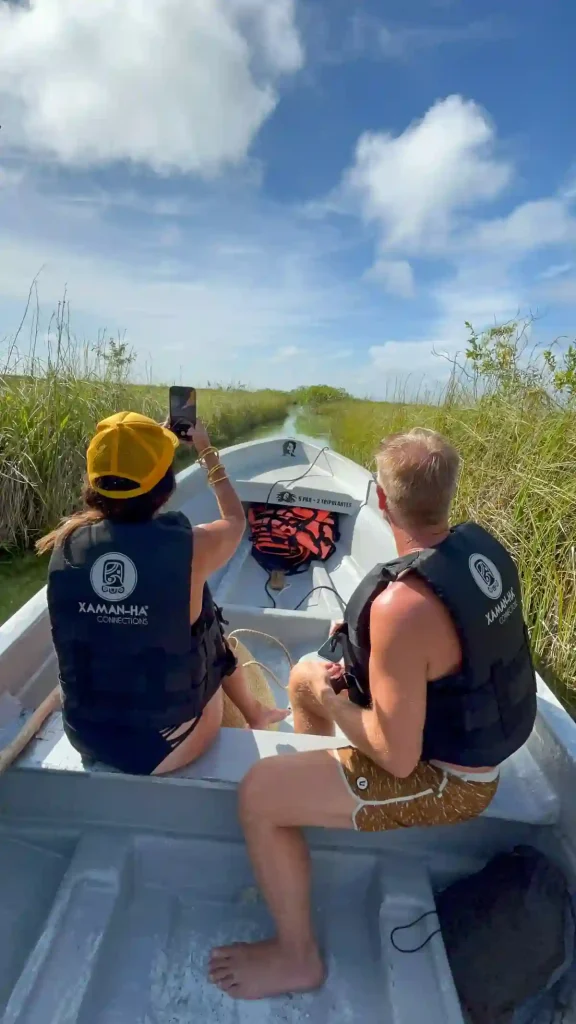 A couple on a private boat ride through narrow Muyil canals surrounded by tall grasses.