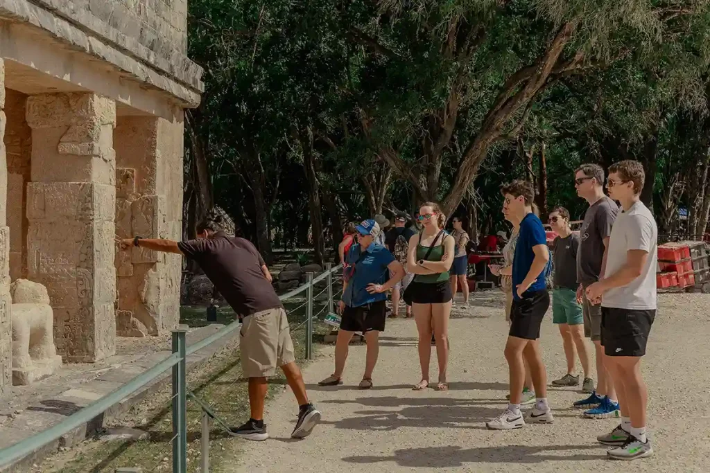 Xaman-Ha Connections certified tour guide explaining Mayan ruins at Chichen Itza to a group of tourists during a private excursion.