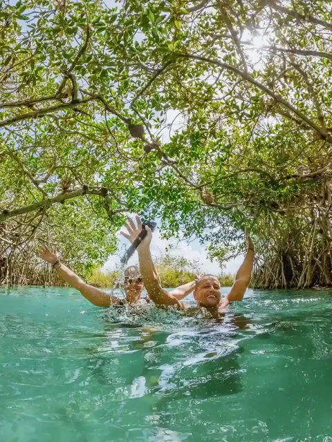 Couple swimming joyfully through the lush Muyil canals in Tulum.