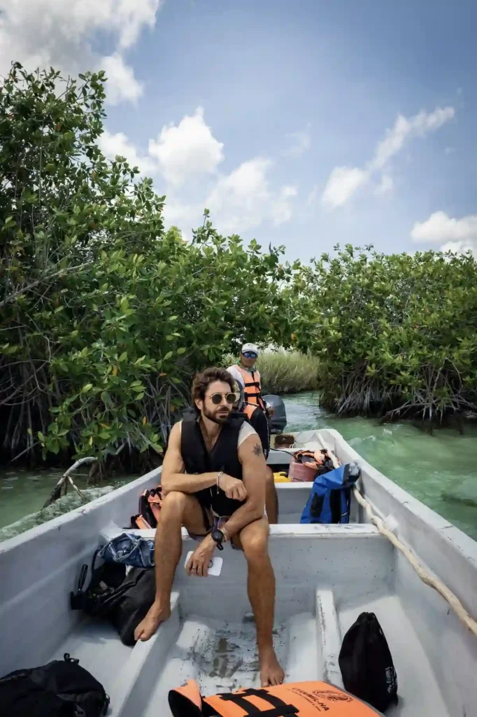 Man on a guided boat tour navigating through lush Muyil jungle waterways.