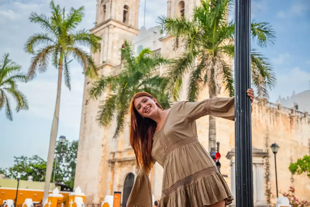 Smiling couple exploring the colonial city of Valladolid with palm trees and historic church towers in the background.