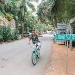 Tourist riding a bicycle in Tulum hotel area.