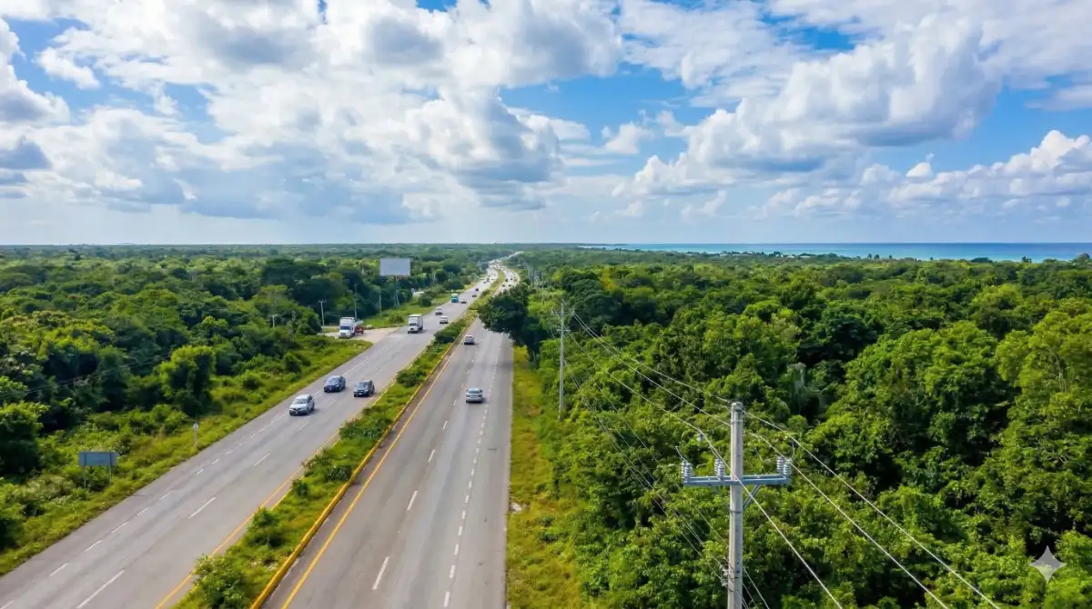 Aerial view of highway near Tulum surrounded by jungle with the Caribbean coast visible in the distance.