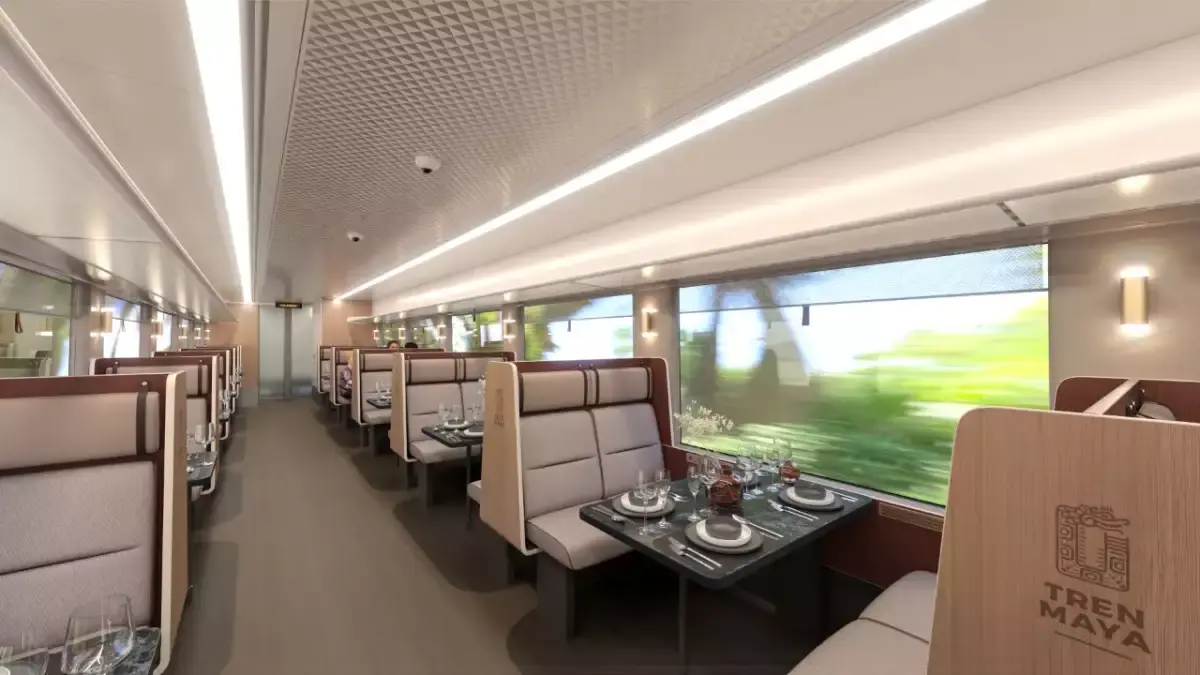 Interior view of Tren Maya train showing modern seating and dining tables for passengers in Mexico.