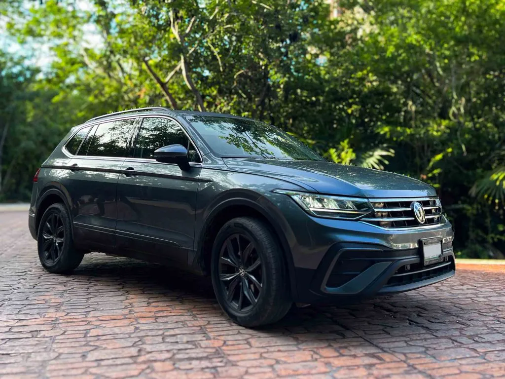A Grey-Blue Volkswagen Tiguan SUV Parked next to some bushes.