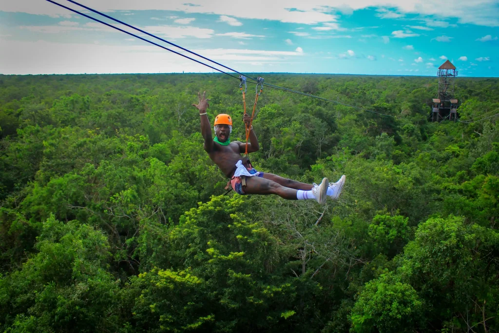 A tourist smiling while zip lining in the middle of the jungle in Tulum.