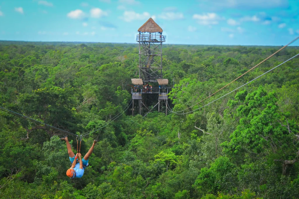 Men zip lining upside down over lush jungle canopy in Tulum.