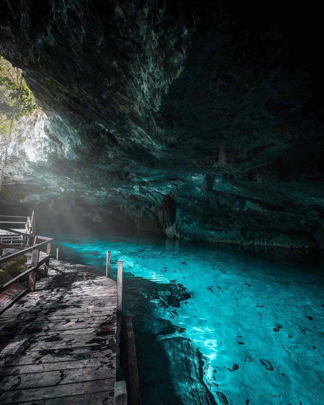 Angle view of Cenote Dos Ojos, the best cenote in Tulum, featuring clear water, rocky formations, and a semi-open cave entrance.





