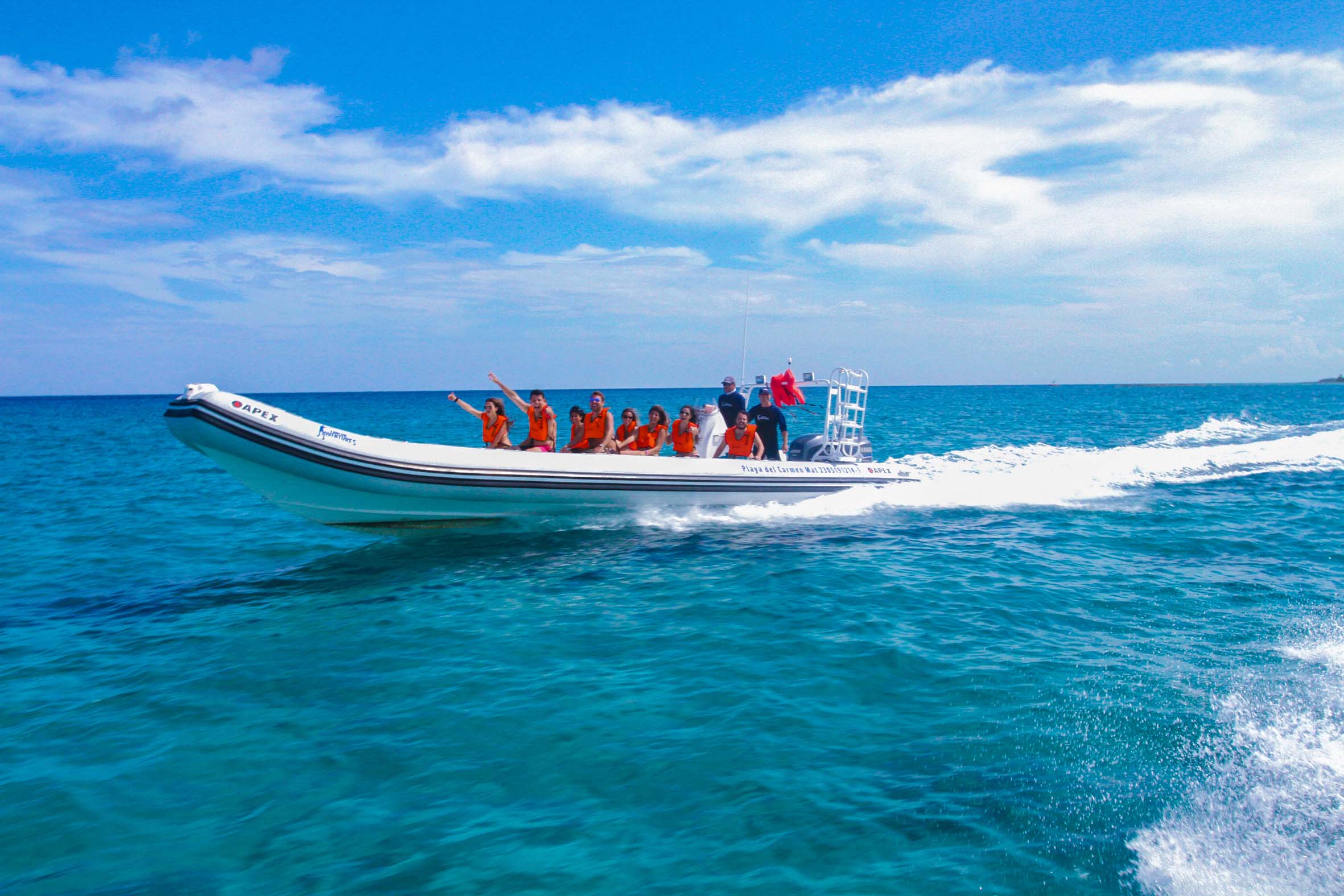 An Apex speedboat cruising through the ocean in Cozumel, filled with excited tourists enjoying the ride.