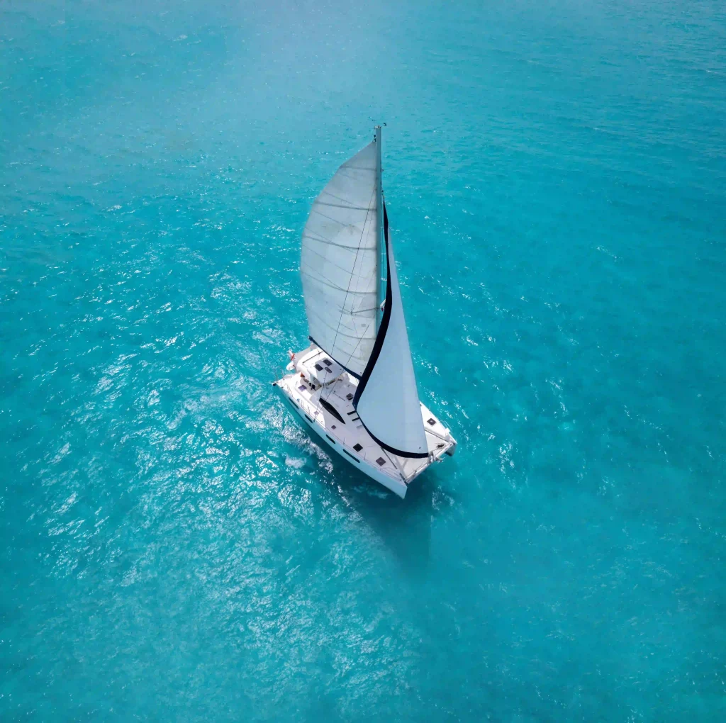 Aerial view of a catamaran sailing through the crystal-clear waters of Cancun's Caribbean Sea.