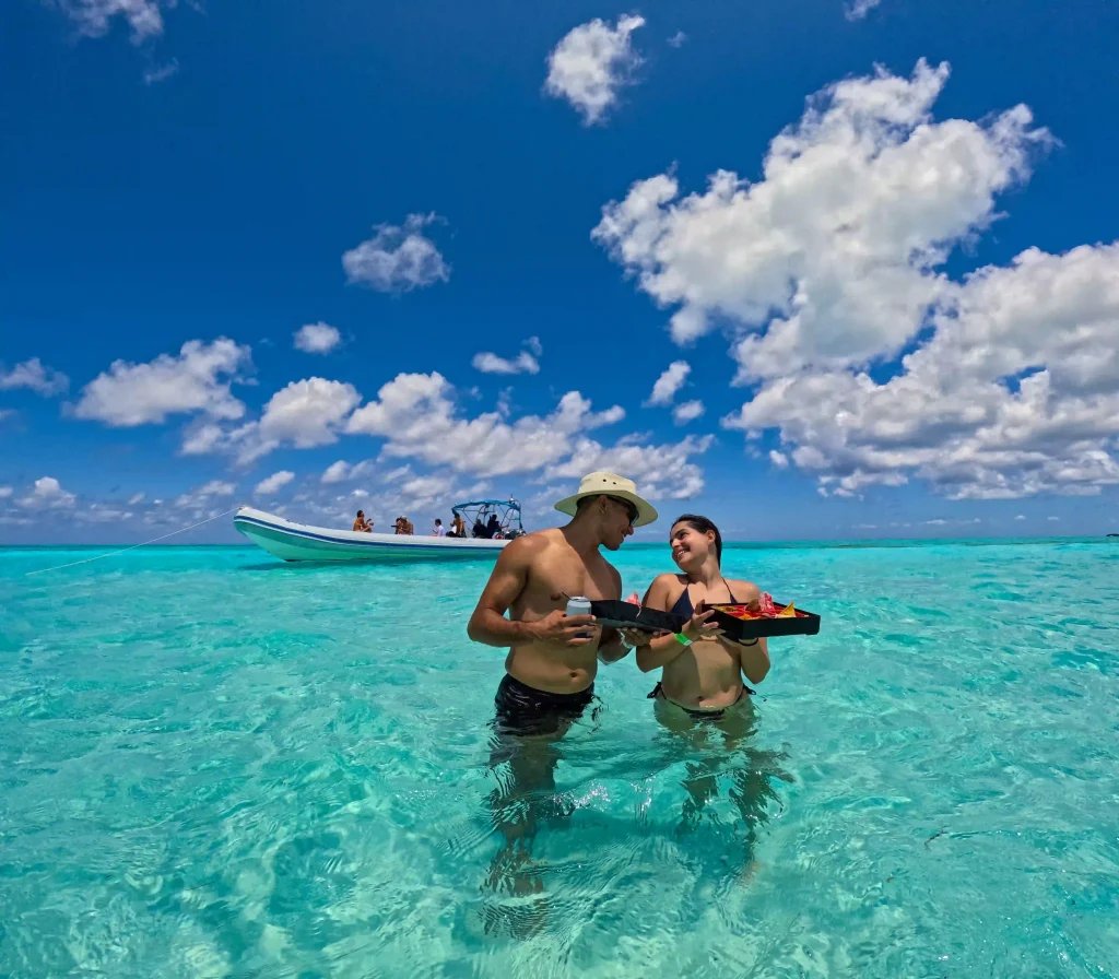 A couple enjoying lunch outdoors by the ocean in a small, secluded inlet, with picturesque coastal views surrounding them.