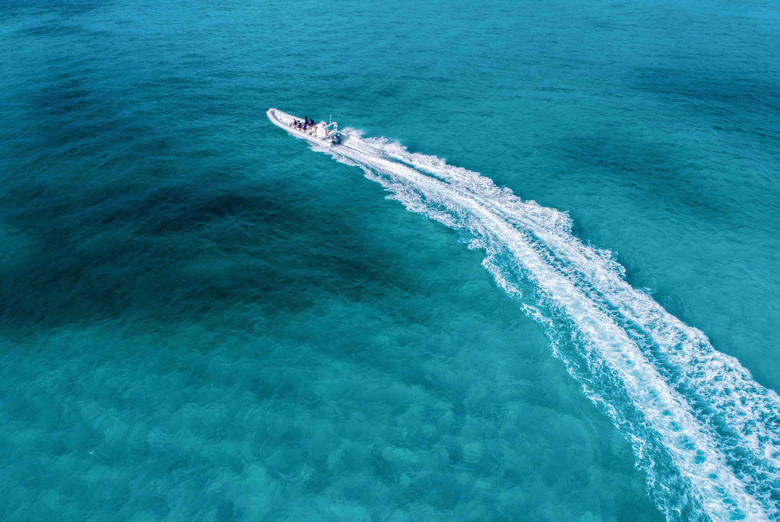Side view of an Apex speedboat cutting through the ocean waves, showcasing its sleek design and speed as it sails across the water