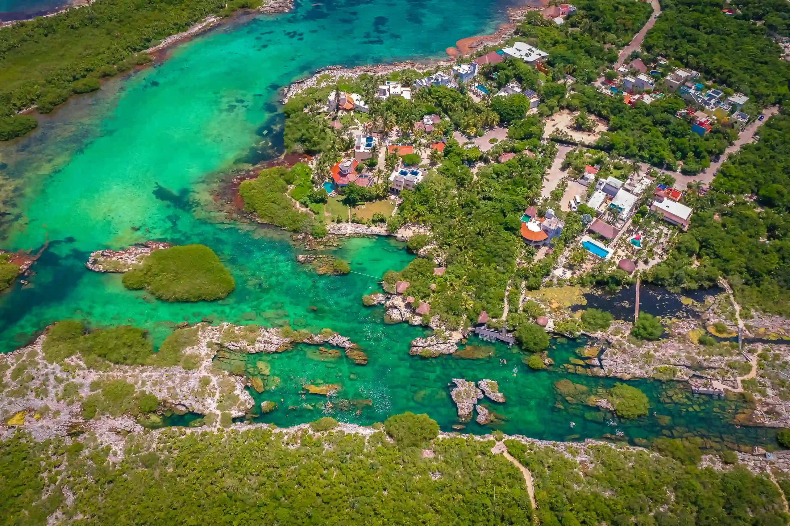 Mayan ruin in Tulum, Mexico, showcasing a large stone structure under a bright sunny sky, surrounded by palm trees and sandy pathways