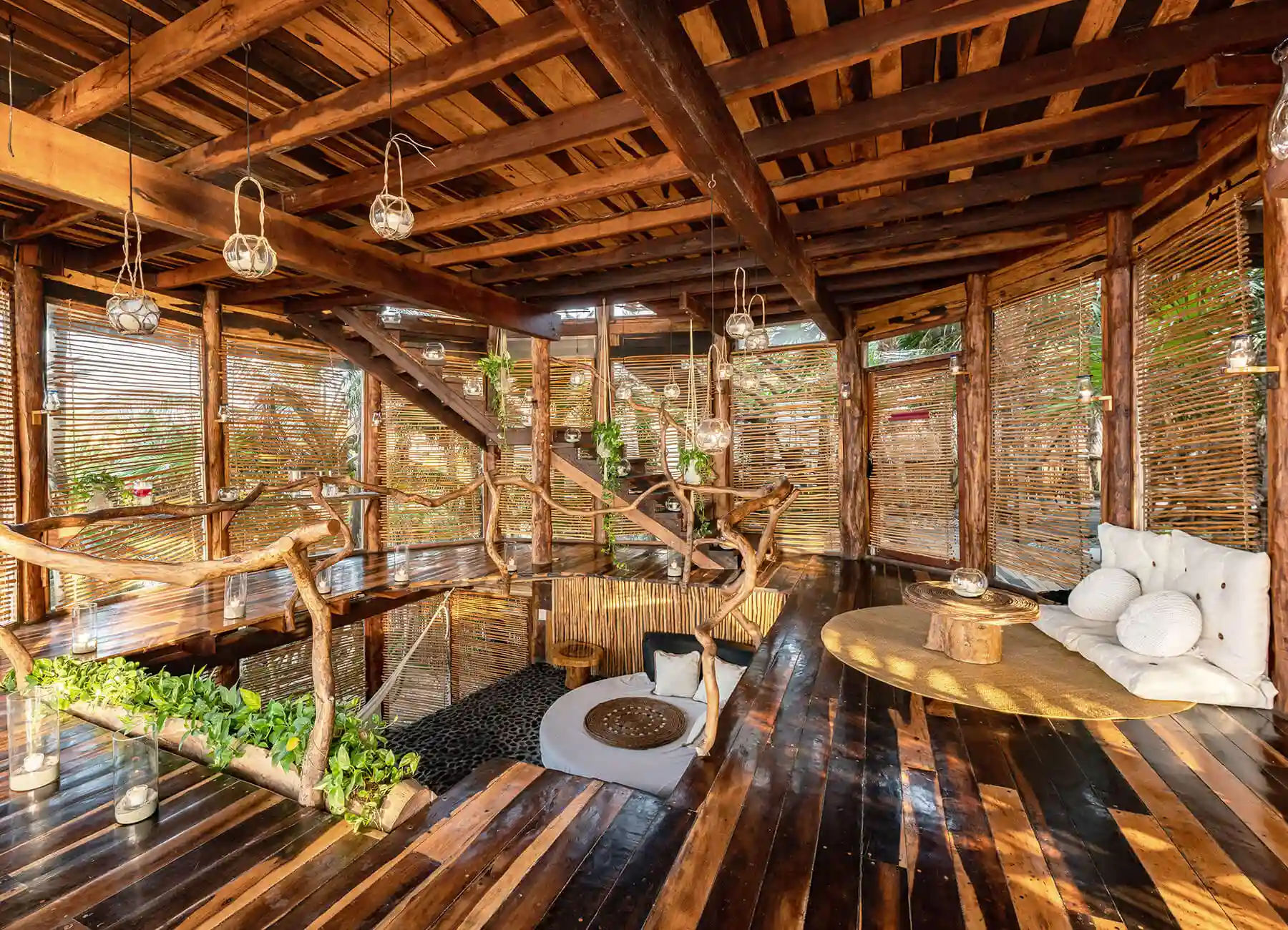 Eco-friendly treehouse interior of a boutique hotel in Tulum with wood beams, wicker accents, and jungle views.