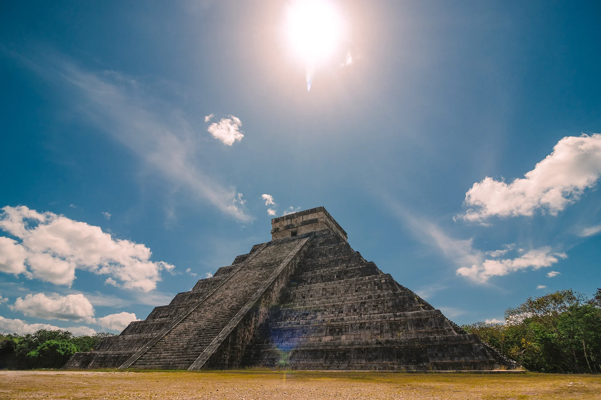 The Kukulkan Pyramid at Chichen Itza under a bright, sunny sky. 