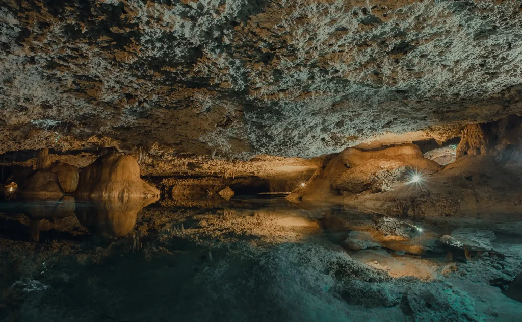A breathtaking view of a natural underground cenote surrounded by intricate rock formations.