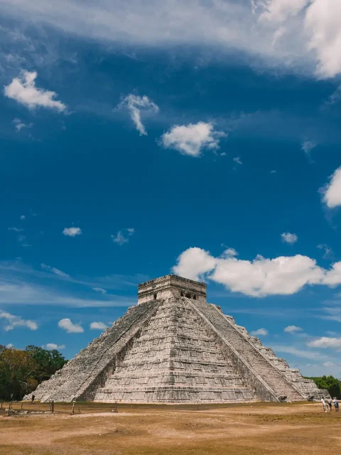 The iconic Kukulkan Pyramid at Chichen Itza, a UNESCO World Heritage site in Yucatan, Mexico, under a bright blue sky.