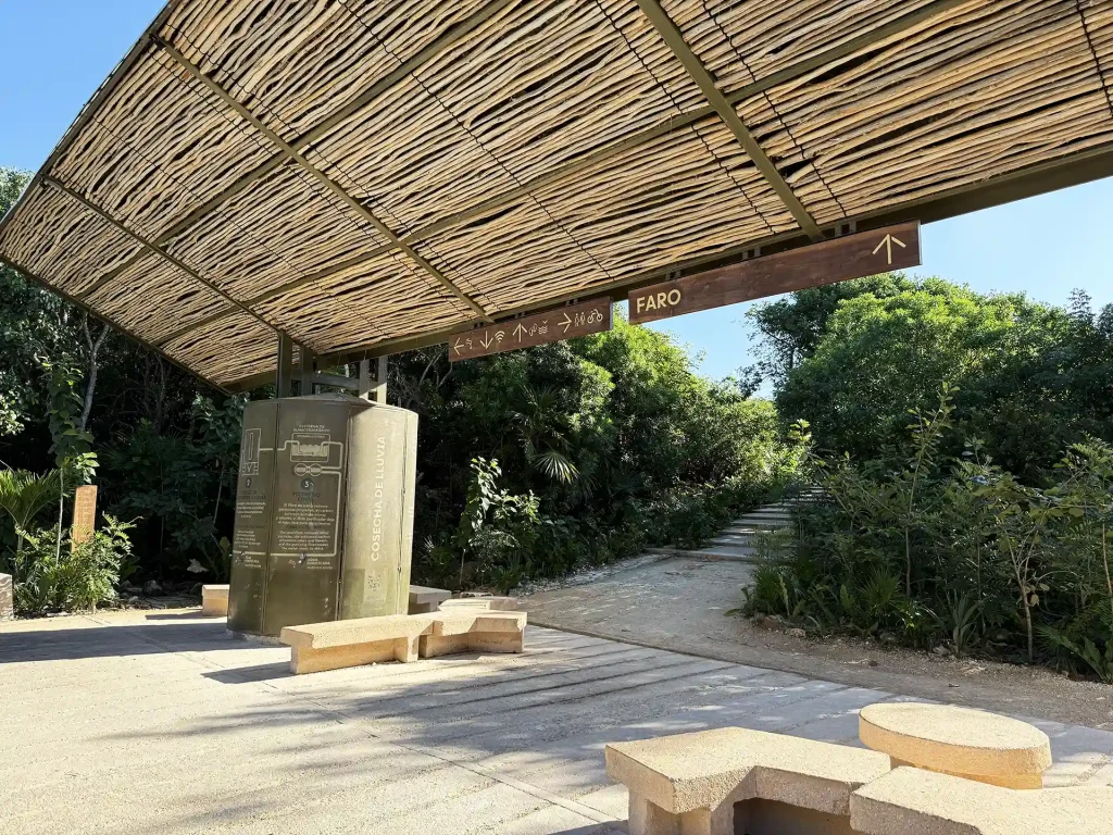Tulum Archaeological Site train station with a bamboo-covered waiting area, informational signage.