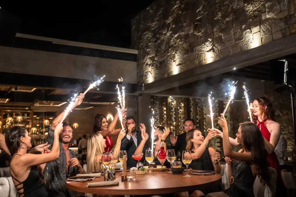 Elegant dinner celebration at a high-end Tulum restaurant, where guests enjoy drinks and gourmet food.
