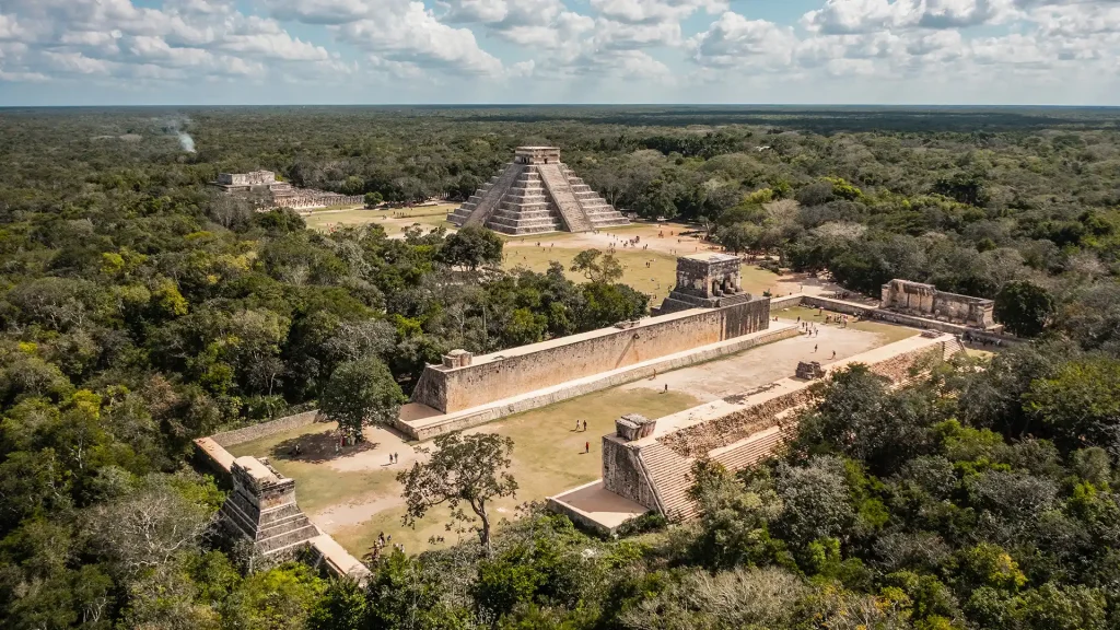 Aerial view of Chichen Itza highlights the iconic El Castillo pyramid and surrounding structures nestled in the Yucatán jungle.