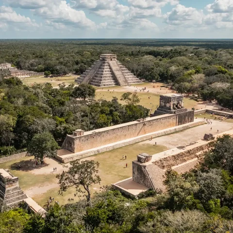 Aerial view of Chichen Itza highlights the iconic El Castillo pyramid and surrounding structures nestled in the Yucatán jungle.