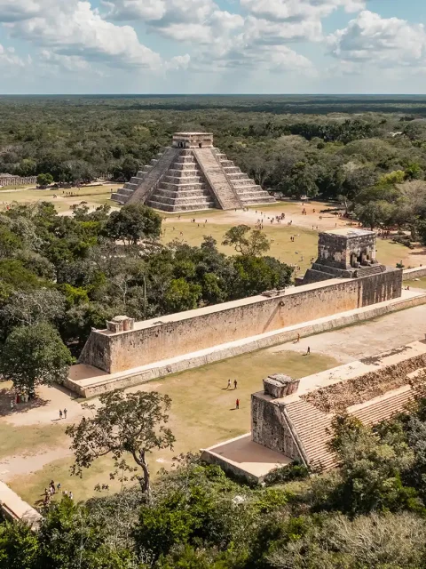 Aerial view of Chichen Itza highlights the iconic El Castillo pyramid and surrounding structures nestled in the Yucatán jungle.
