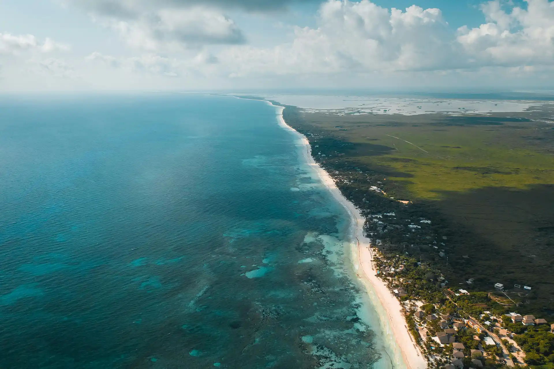 Aerial view showcasing the stunning beachside location of Tulum, where turquoise waters meet white sand and lush jungle surroundings.