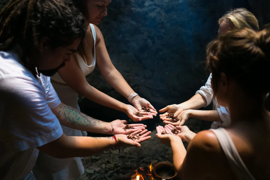 Group of people participating in a traditional cacao ceremony, holding cacao beans in their hands.
