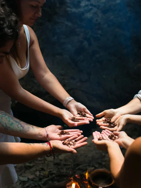 Group of people participating in a traditional cacao ceremony, holding cacao beans in their hands.