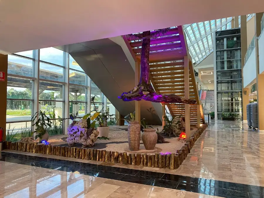 Interior of Tulum International Airport terminal featuring modern architecture with tropical design elements and staircase.