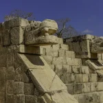 Stone serpent head sculptures at the Temple of Kukulkan in Chichen Itza, representing ancient Maya mythology.