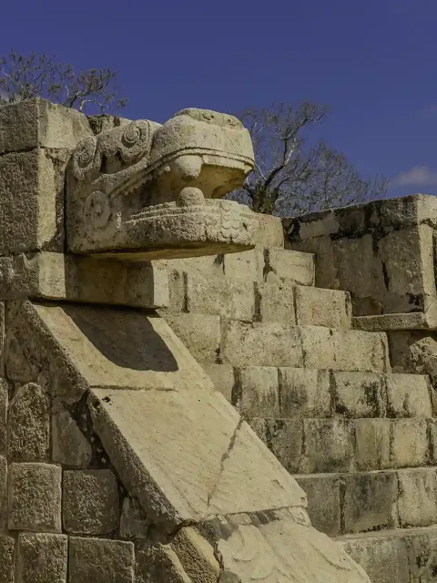 Stone serpent head sculptures at the Temple of Kukulkan in Chichen Itza, representing ancient Maya mythology.