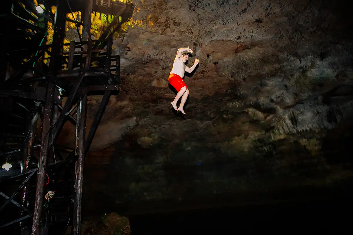 Man jumping into a cenote from the Coba cave platform.