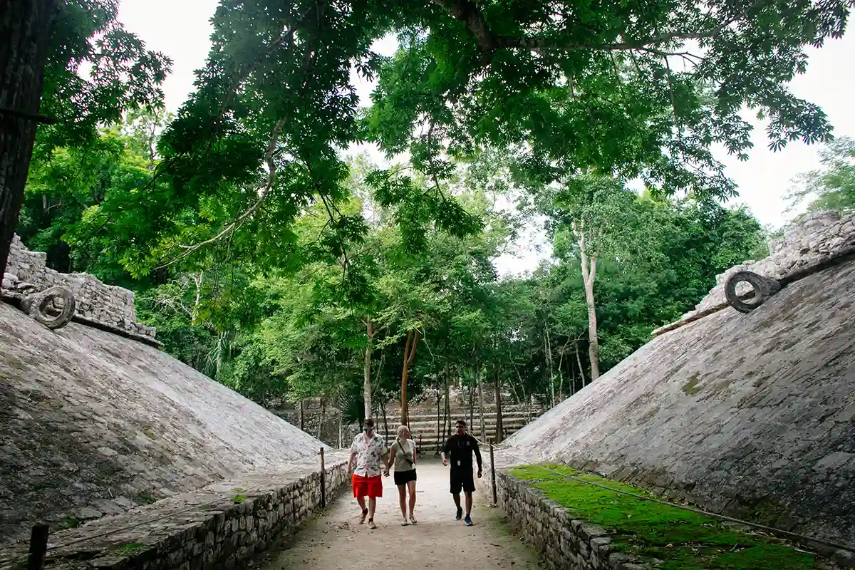 Tour guide walking with couple through ancient Coba ball court.
