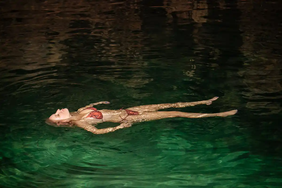Woman floating in an underground cenote cave.