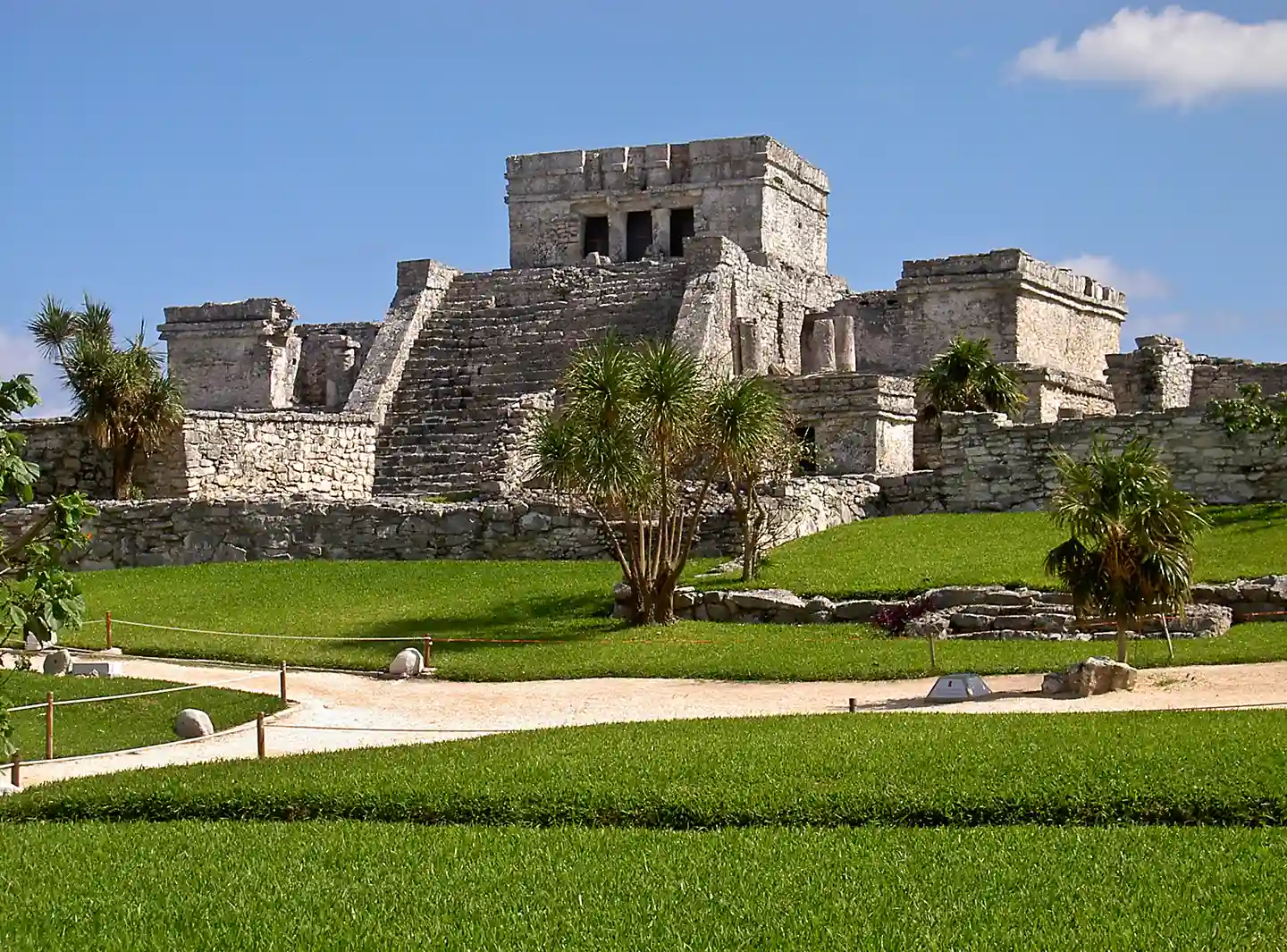 Ancient Mayan temple ruins at Tulum, perched on a grassy hill.
