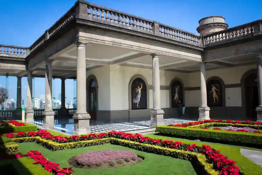 Beautiful inner courtyard garden of Chapultepec Castle with colorful flowers, stone columns, and classical architecture in Mexico City.