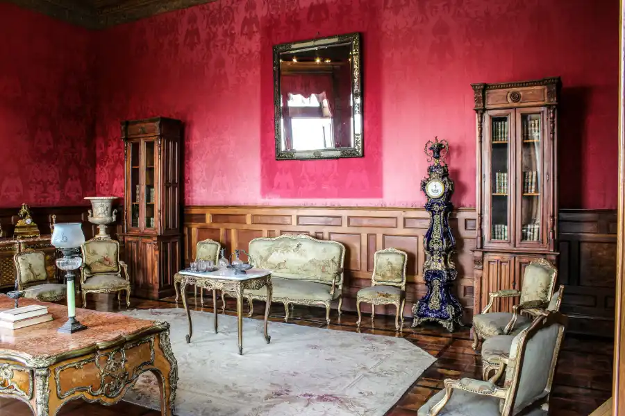 Luxurious royal salon inside Chapultepec Castle with antique furniture, red damask walls, and vintage decor.