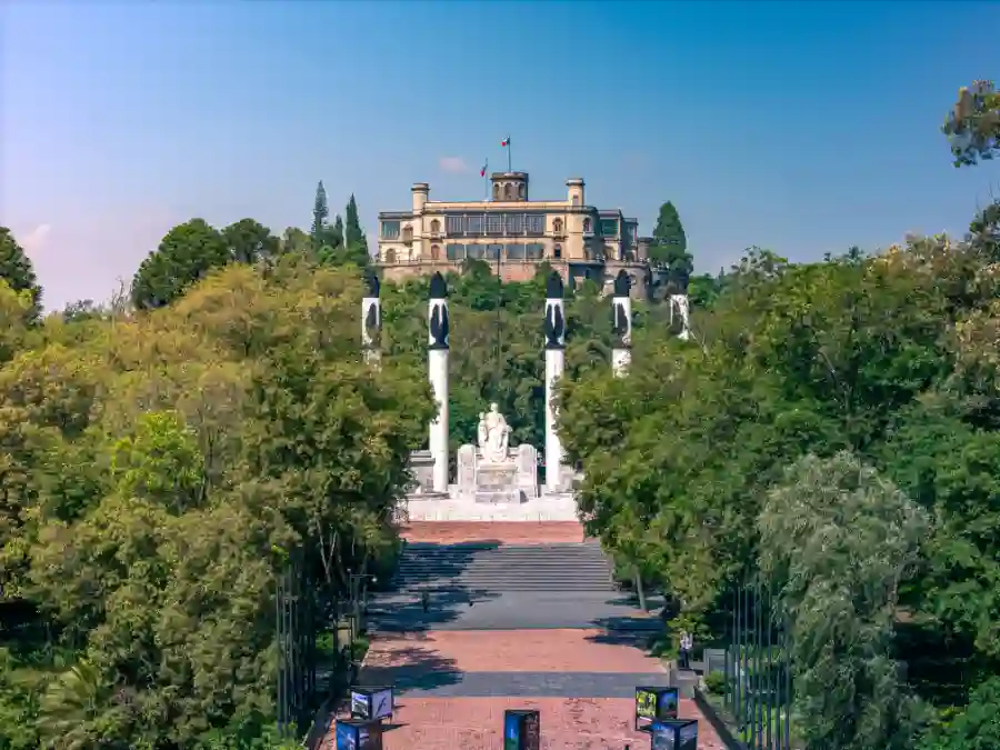 Monument to the Niños Héroes with Chapultepec Castle in the background, surrounded by trees in the heart of Mexico City.