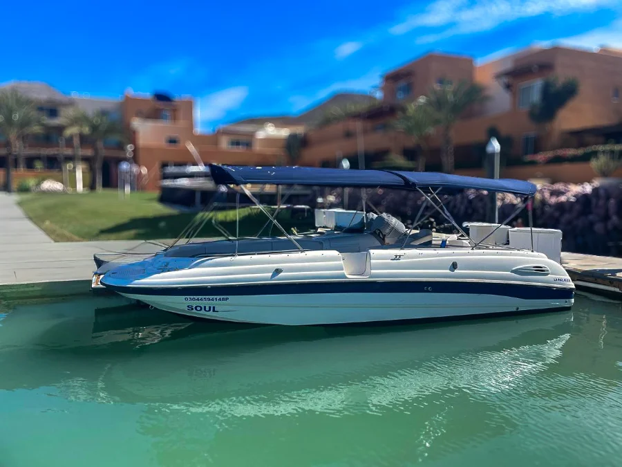 Private speedboat docked at a marina in Cabo San Lucas with waterfront villas and turquoise water in Baja California Sur.