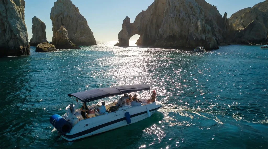 Boat tour near El Arco in Los Cabos at sunset with passengers enjoying the scenic rock formations.