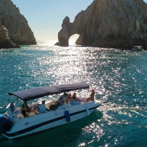 Boat tour near El Arco in Los Cabos at sunset with passengers enjoying the scenic rock formations.