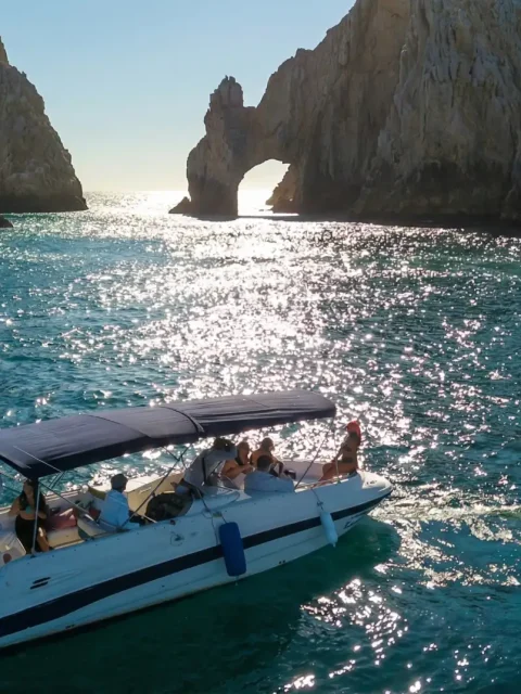 Boat tour near El Arco in Los Cabos at sunset with passengers enjoying the scenic rock formations.