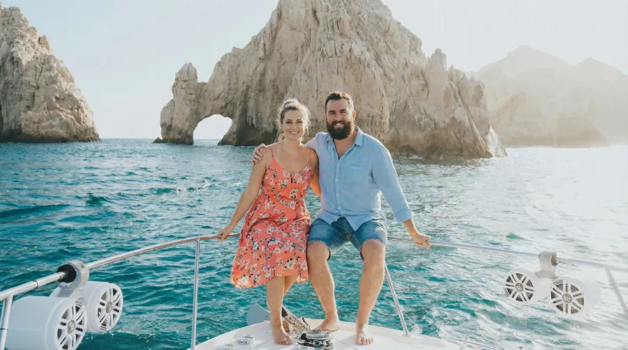 A couple enjoying a boat ride near El Arco during a Los Cabos Arch tour with turquoise waters and rock formations in the background.