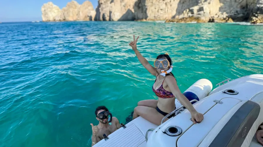 A couple snorkeling in clear turquoise waters during a private boat tour at the Los Cabos arch.