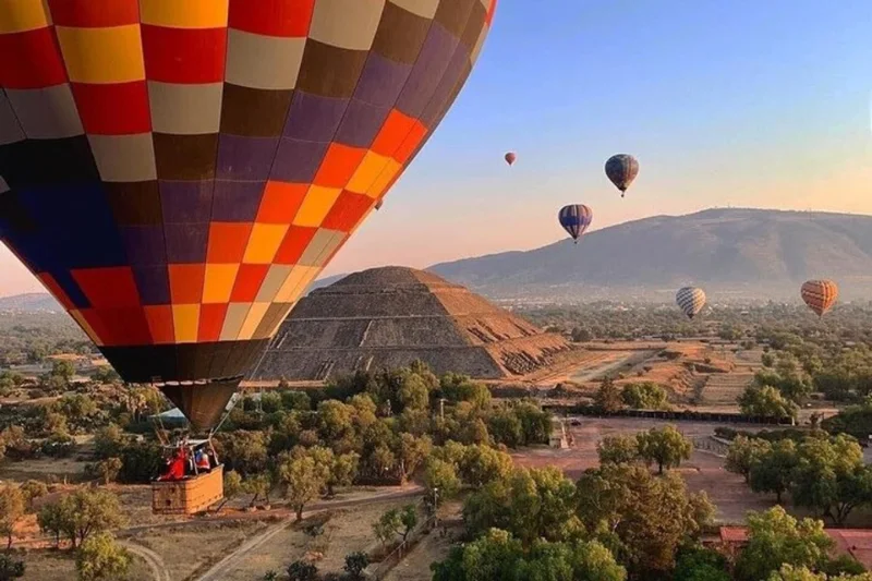 Colorful hot air balloons flying over the Pyramid of the Sun in the archeological site of Teotihuacan.