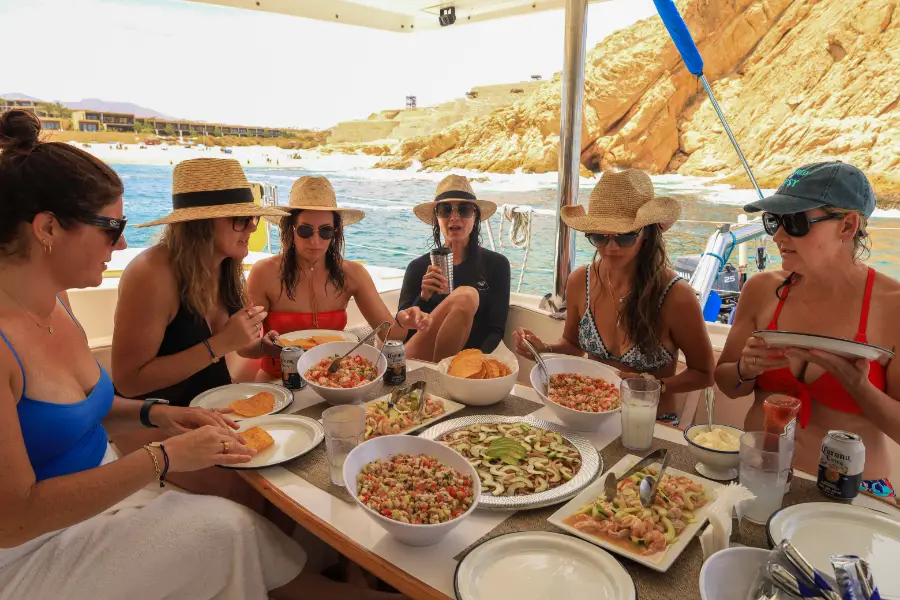 Guests enjoying a fresh lunch and drinks during an all inclusive catamaran Cabo sailing tour along the Cabo San Lucas coastline.
