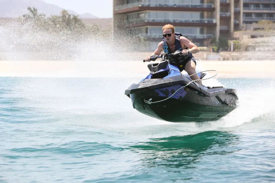 Man riding a jet ski fast along the beach during a Jet Ski rental in Cabo San Lucas.