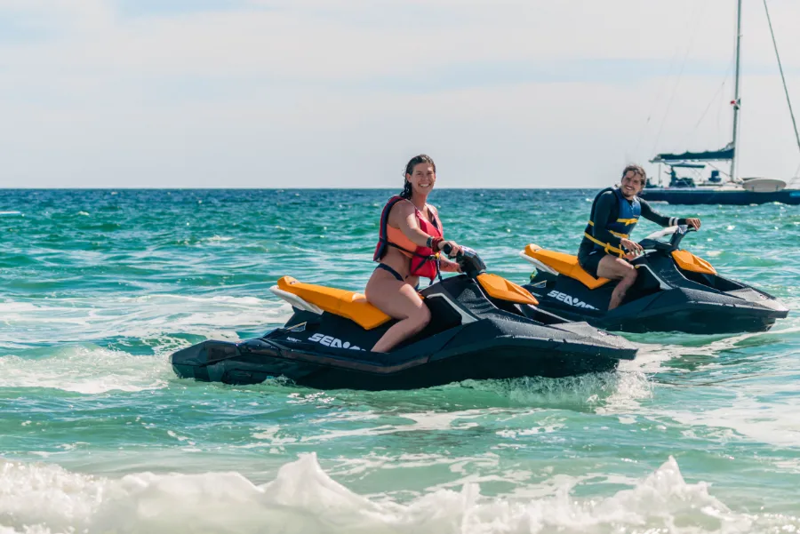 Couple riding jet skis during a Jet Ski Rental in Cabo San Lucas on a Sea of Cortez ocean adventure near the beach.