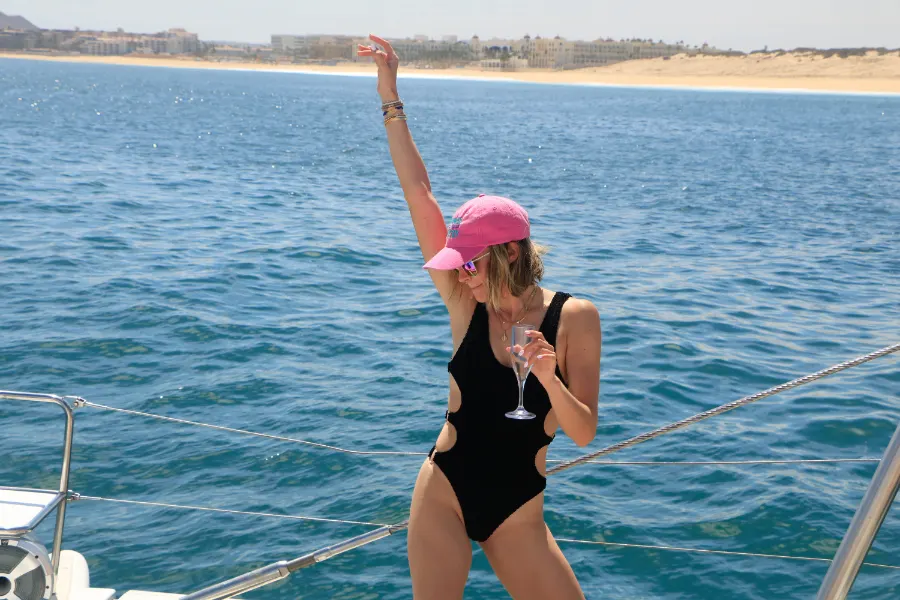 Guest enjoying a drink and dancing on deck during a luxury private catamaran Cabo San Lucas sailing tour.